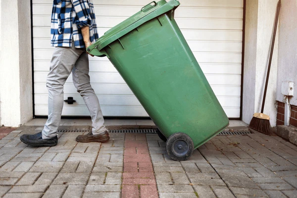 Person rolling a garbage bin